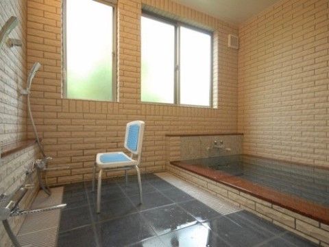 多人数に対応できる広いスペースがある浴室。床と浴槽は黒のタイルで統一され、シックな雰囲気になっている。