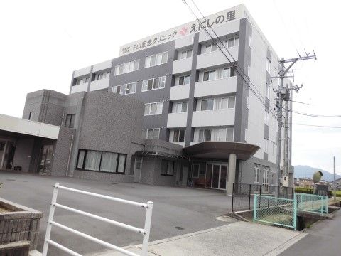 グレーを基調としたモノトーンのモダンな外観。建物上部に施設名の看板が掲げられている。施設周辺には段差が少なくゆとりのある空間を設けている。
