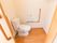 温水洗浄便座が１台設置された個室トイレで、壁にＬ字型の手すりが取りつけられている。手すりの近くにナースコールがある。