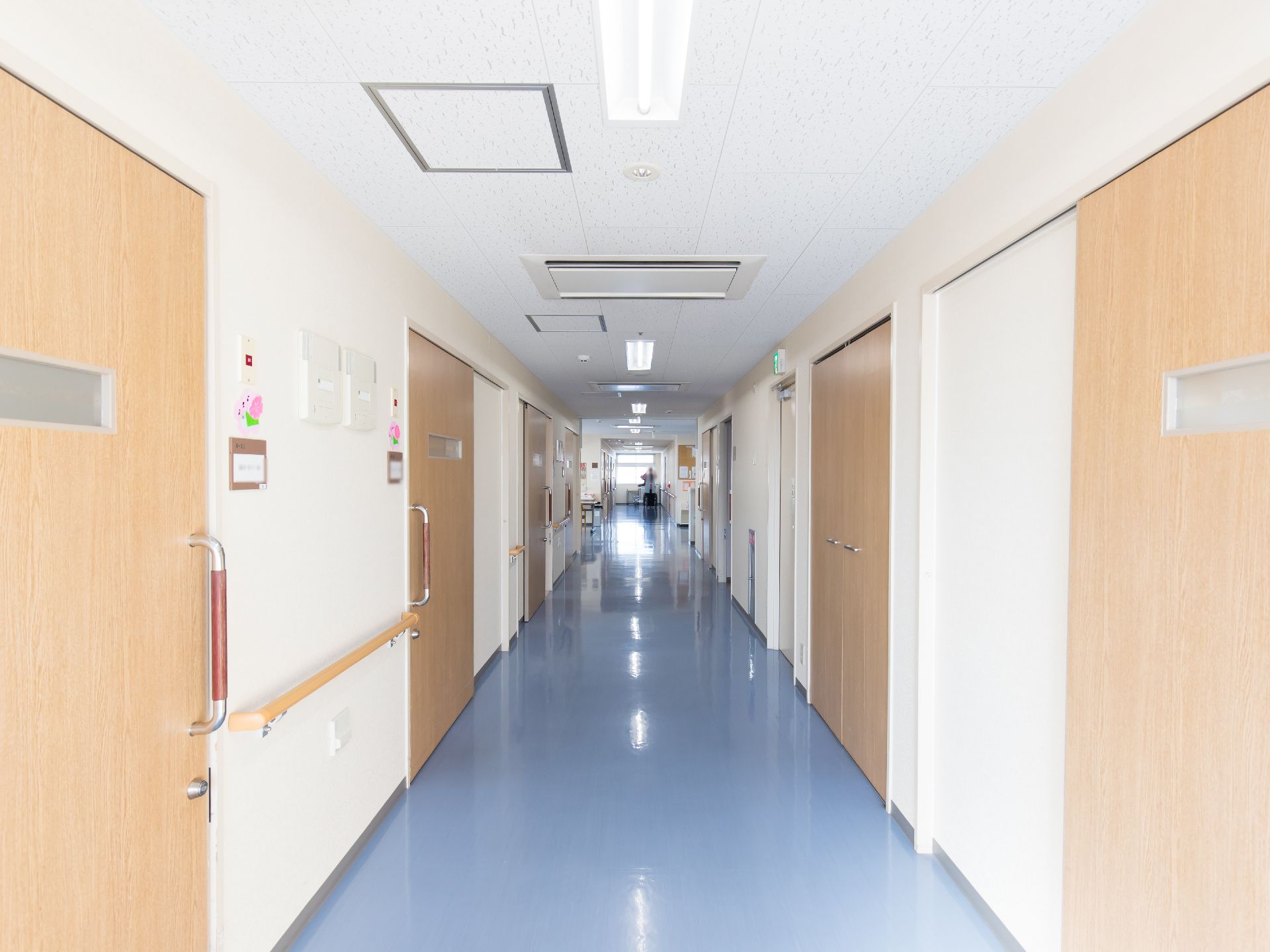 幅にゆとりがある廊下である。青色の床で、壁には手すりが設置されている。外光が窓から入る明るいスペースである。