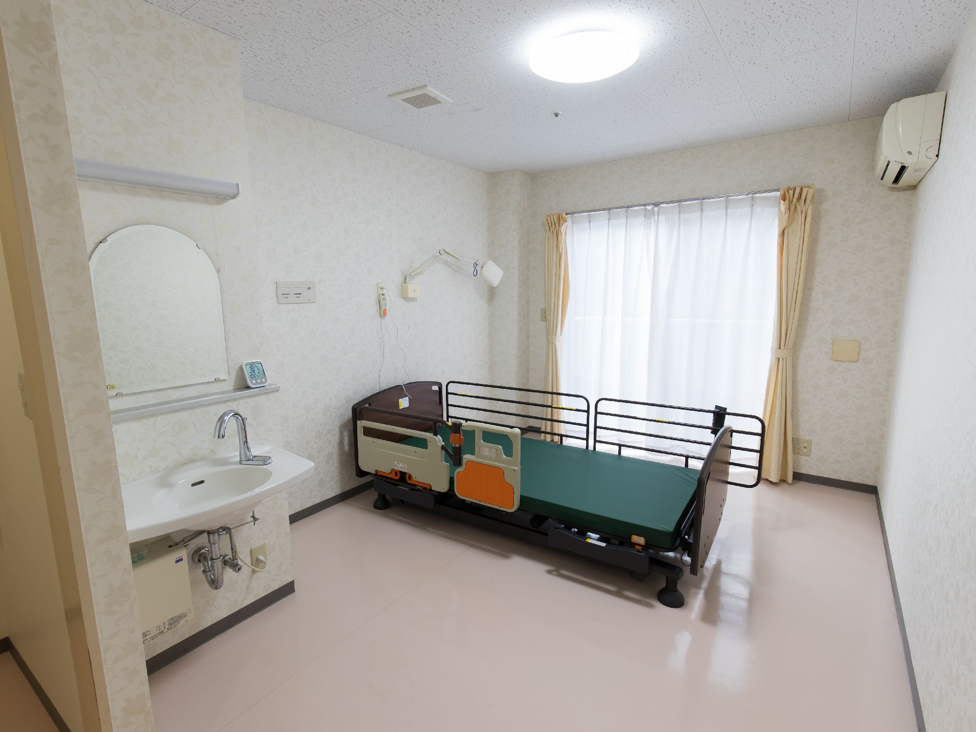 大きな鏡付きの洗面台が隅に設置されていて、中央にベッドがある居室