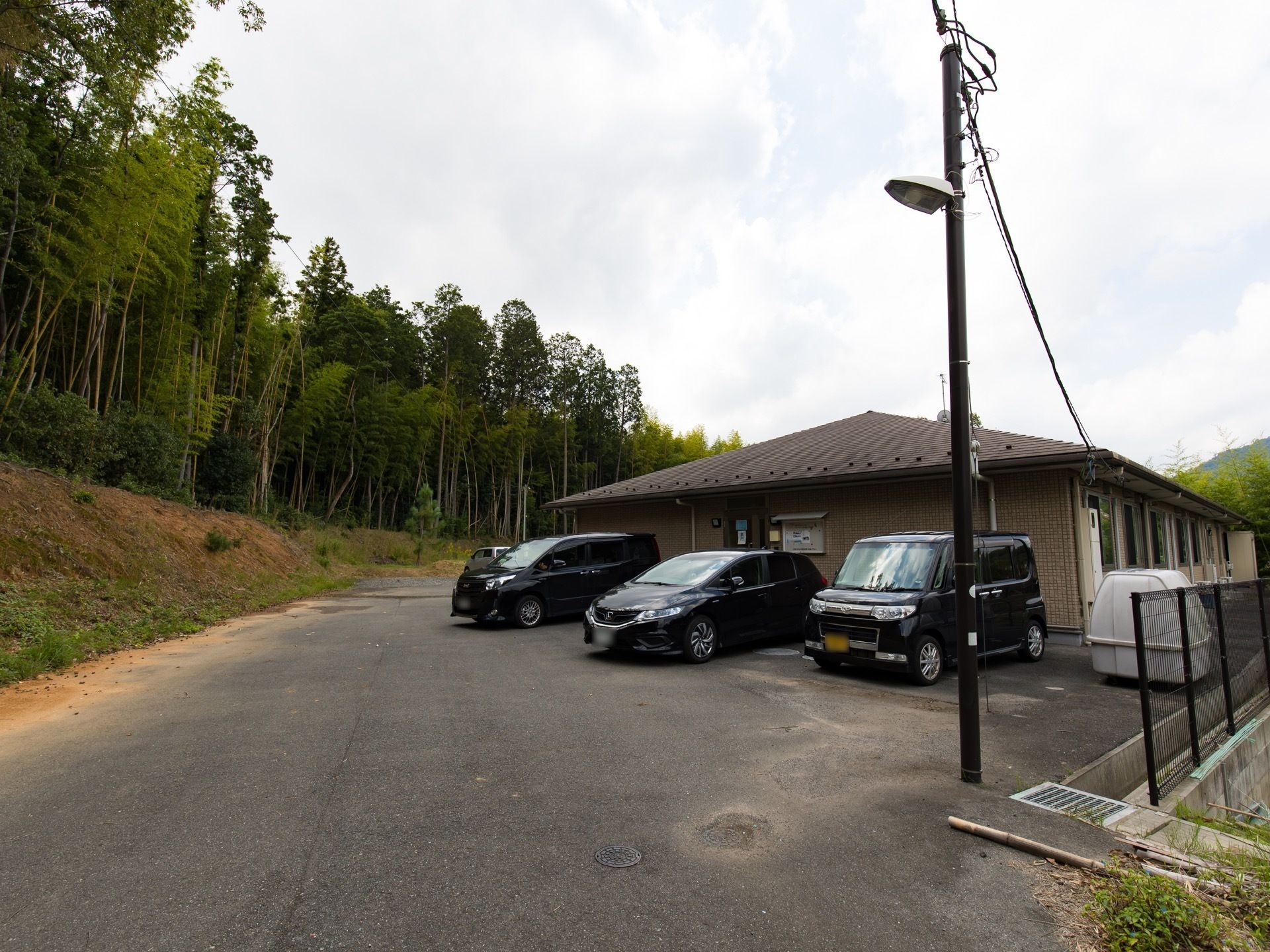 施設は平屋建ての建物である。駐車スペースが建物横に設けられている。周囲には、緑豊かな木々が生えている。