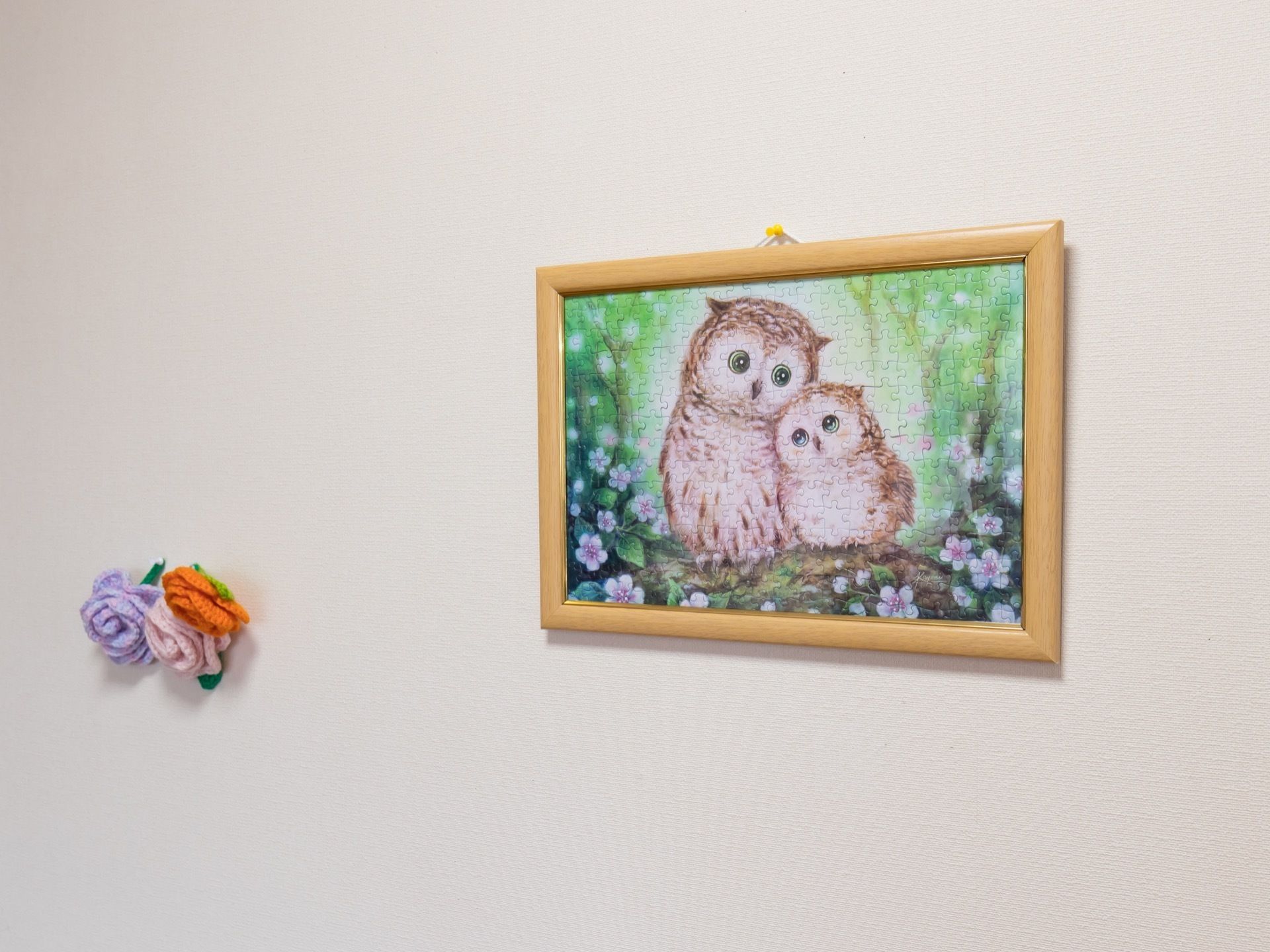壁にフクロウの親子が描かれた絵や毛糸で編まれた３輪の花が飾られており、共有スペースに彩を添えている。