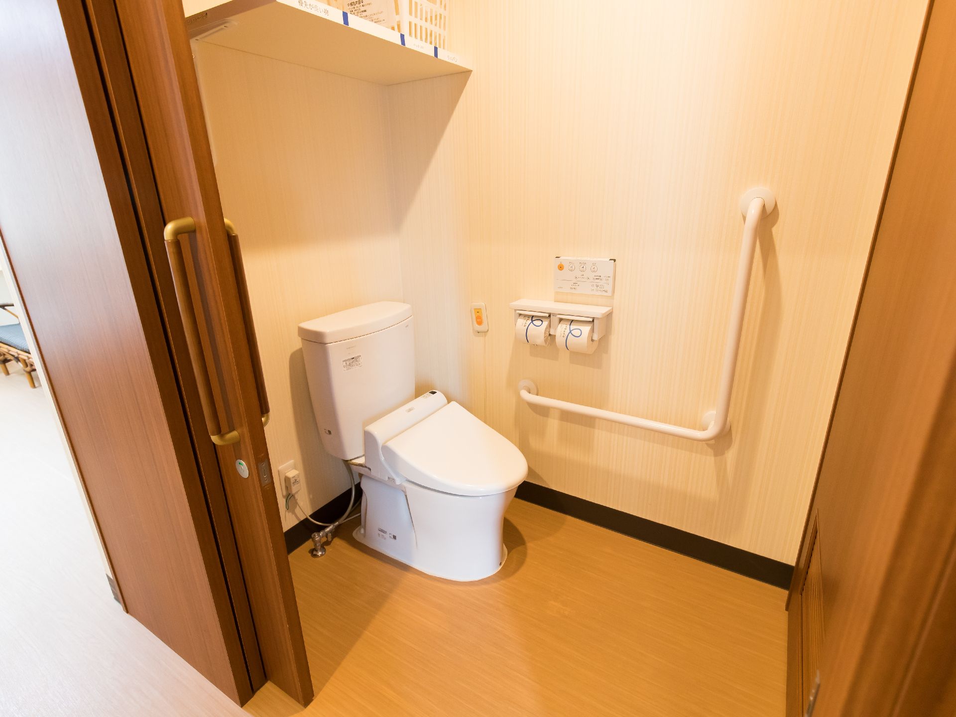 引き戸で広く扉が開く、温水洗浄便座と手すりがついたトイレ