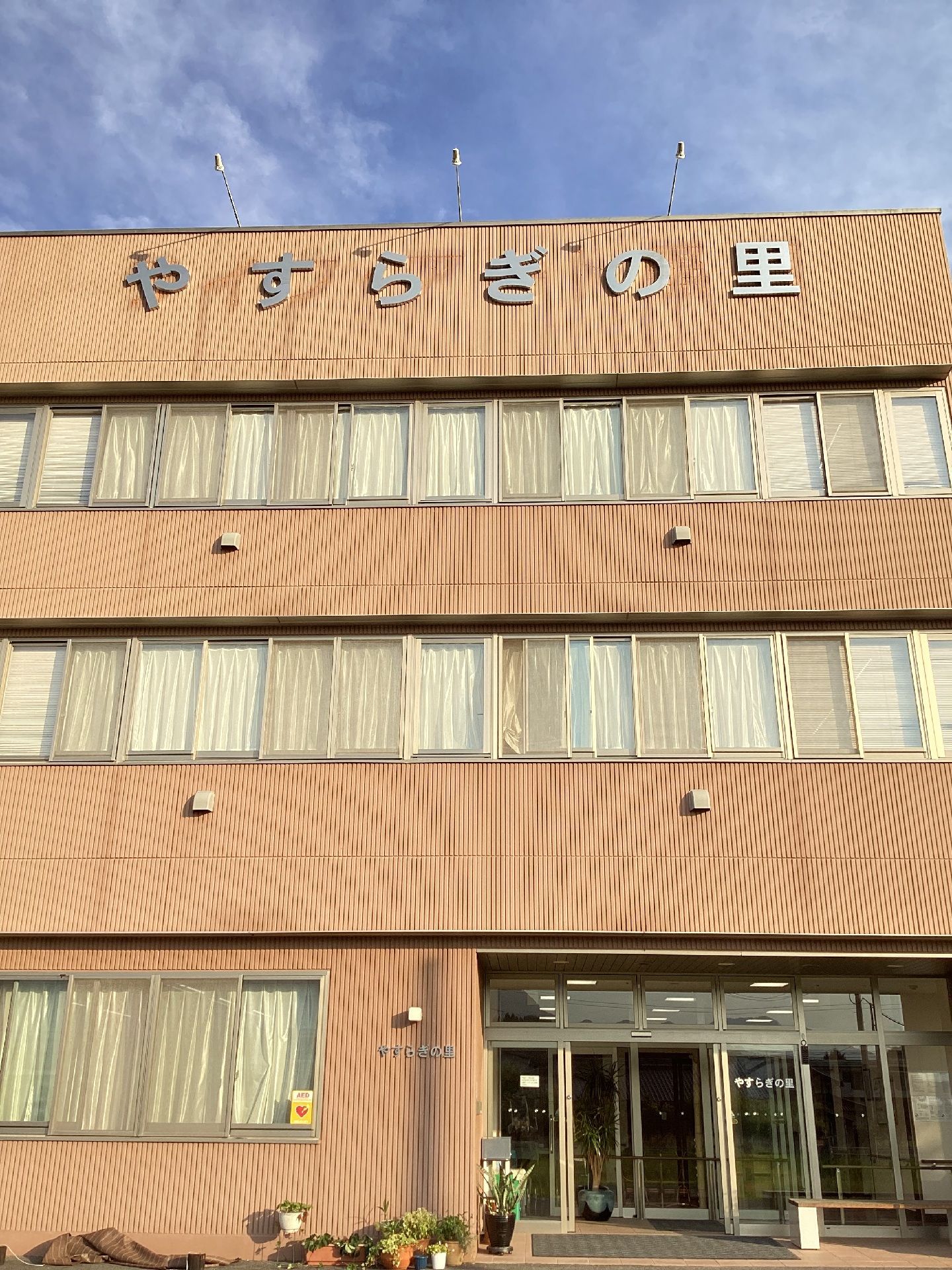 ３階建てのツートンカラーの建造物である。駐車場が完備されている。玄関スペースは段差もなく、広々としている。