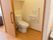 居室名にあるトイレであり、扉はスライド式でフローリングの床である。壁にL字の手すりや緊急時用のコールが設置される。