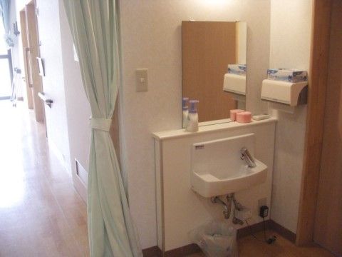施設内の廊下の一角には、高さの低い簡易洗面台が設置されている。正面の壁には、大きな鏡も取りつけられている。