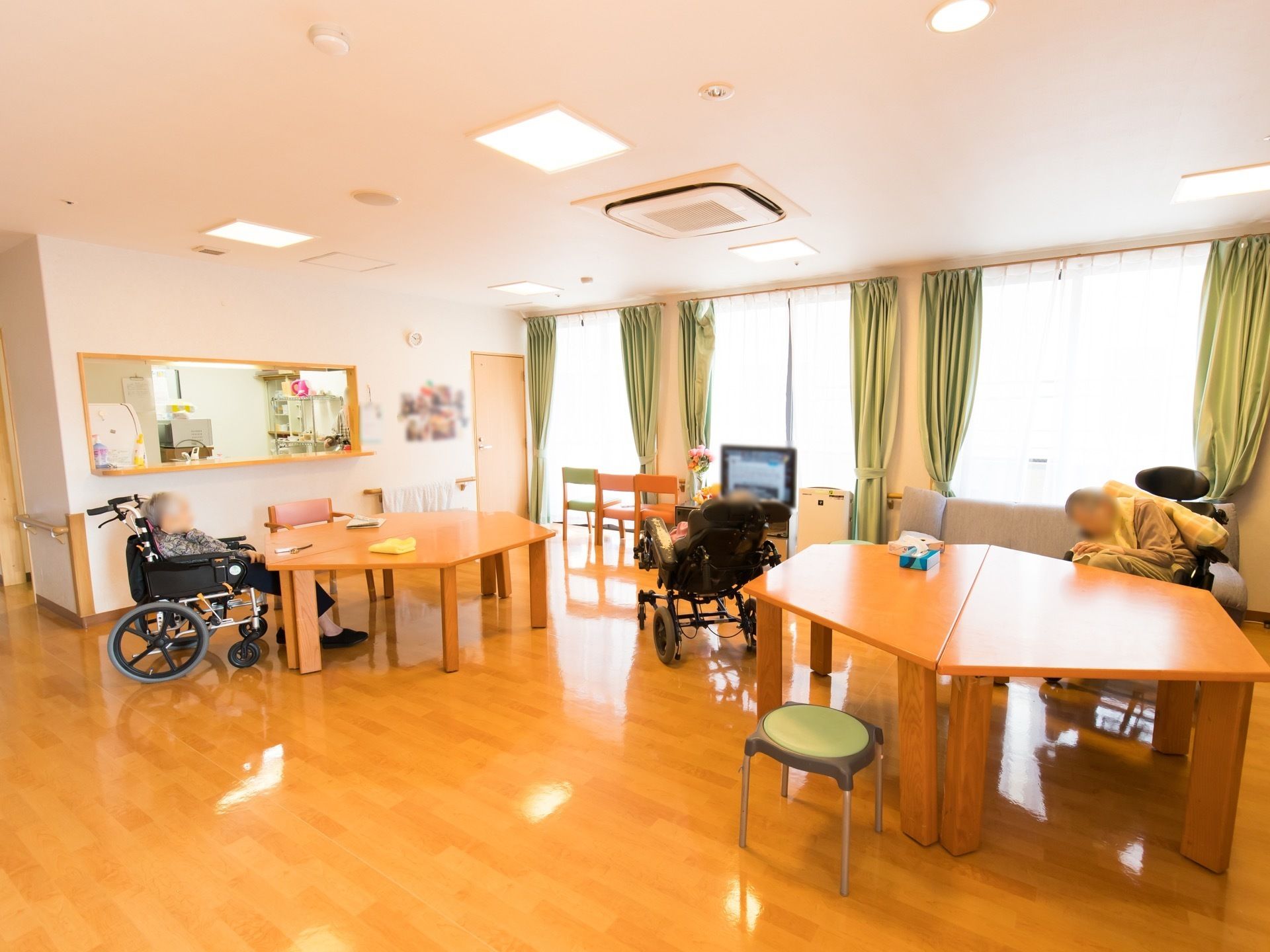 広々とした食堂には、6角形のテーブルと椅子が用意されている。車椅子に乗った3人の入居者様が、ゆったりと休憩している。