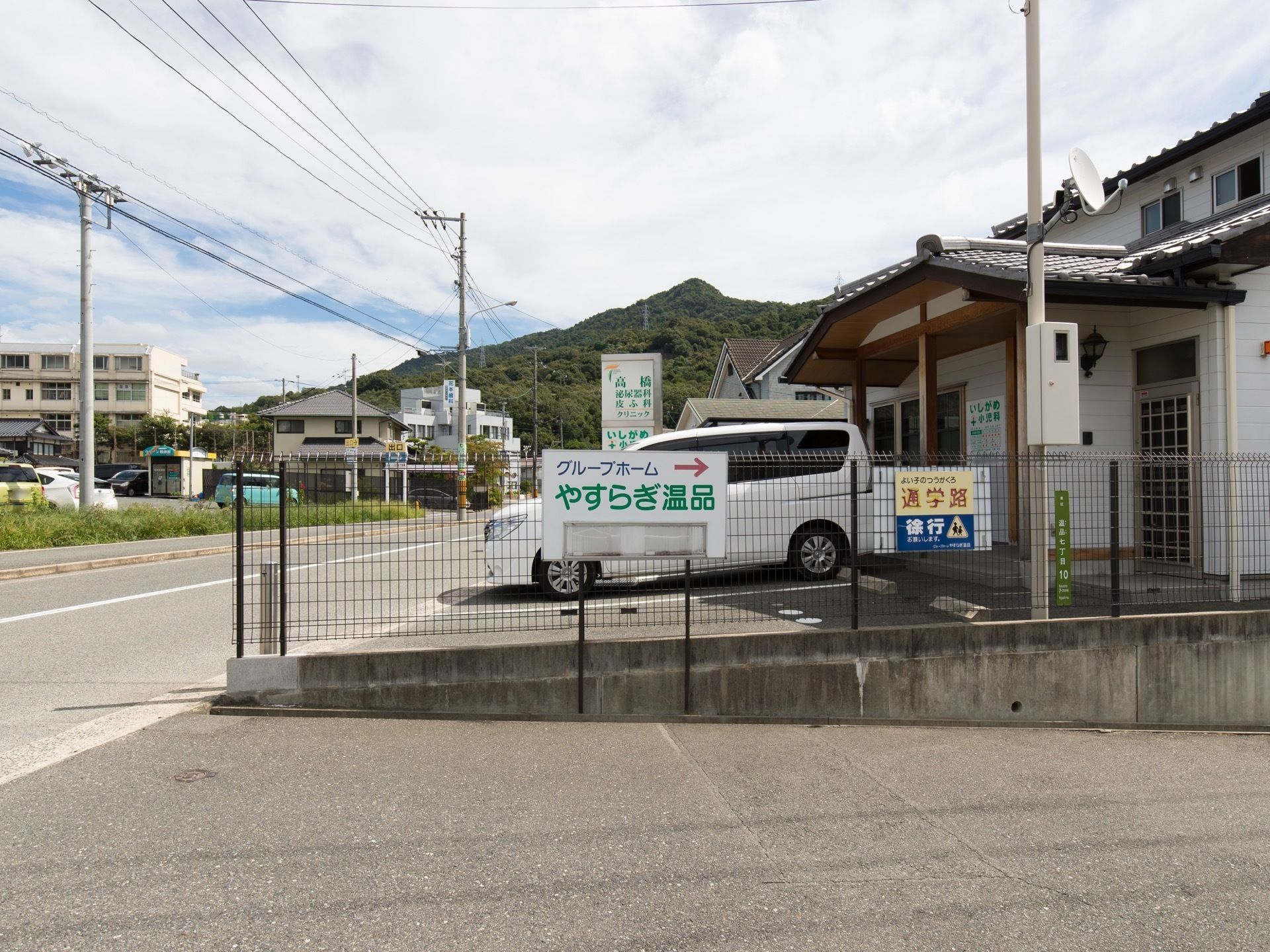 隣の建物とはフェンスで仕切られており、施設名が記された看板が敷地の出入り口付近に取りつけられている。