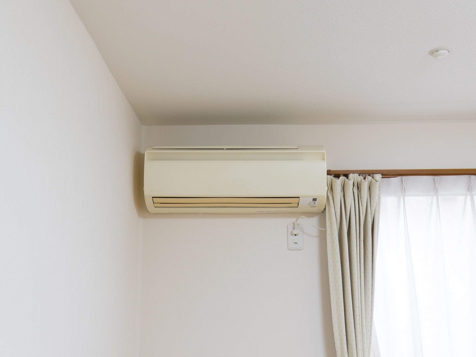 居室には、エアコンが完備されている。日差しが差しこむ窓には、カーテンが掛かっている。火災報知器が天井に設置されている。