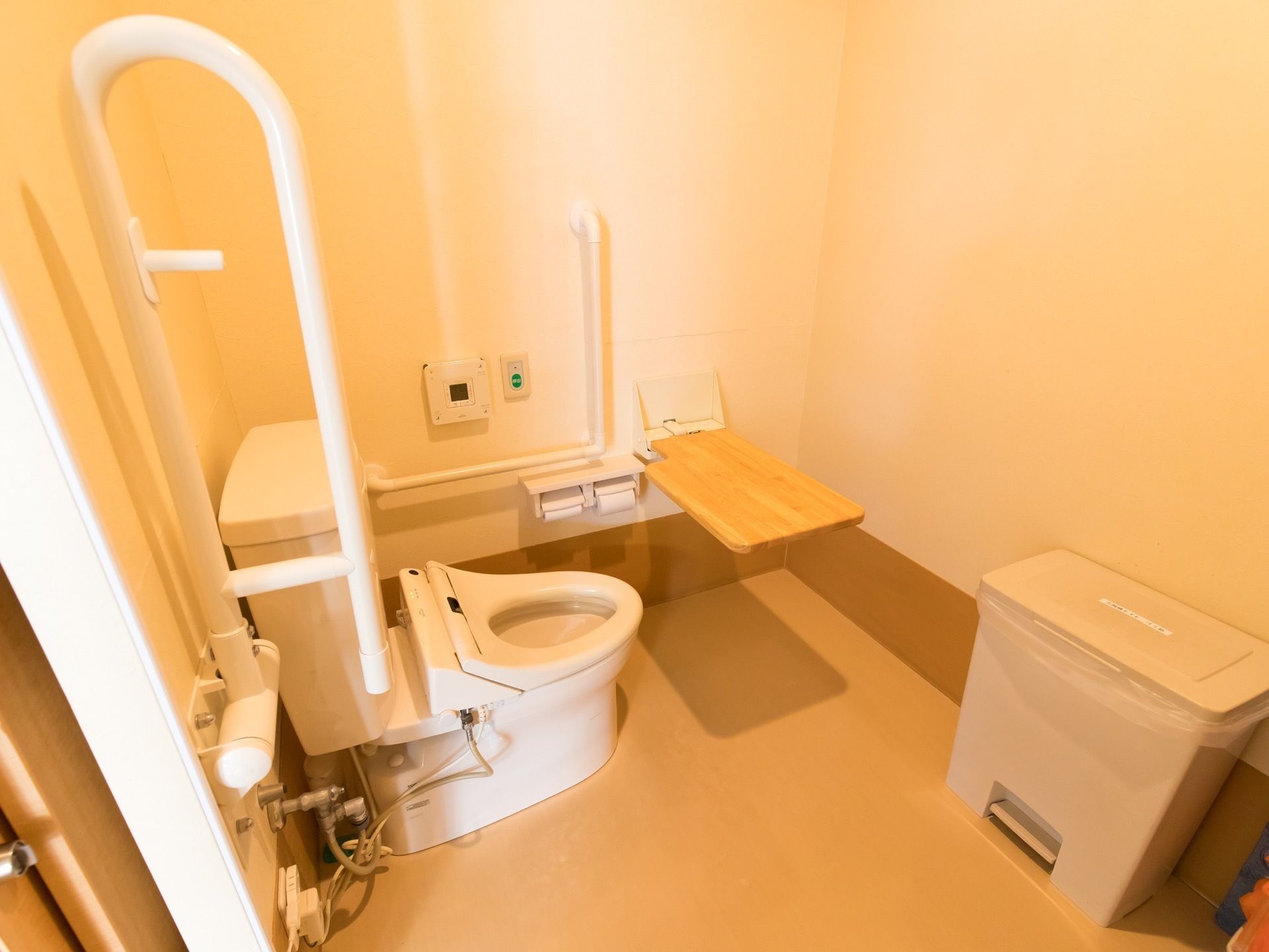 安全で清潔なトイレルームである。便座の両側に固定と可動の手すりが設置してある。広々としたスペースで移動しやすい。