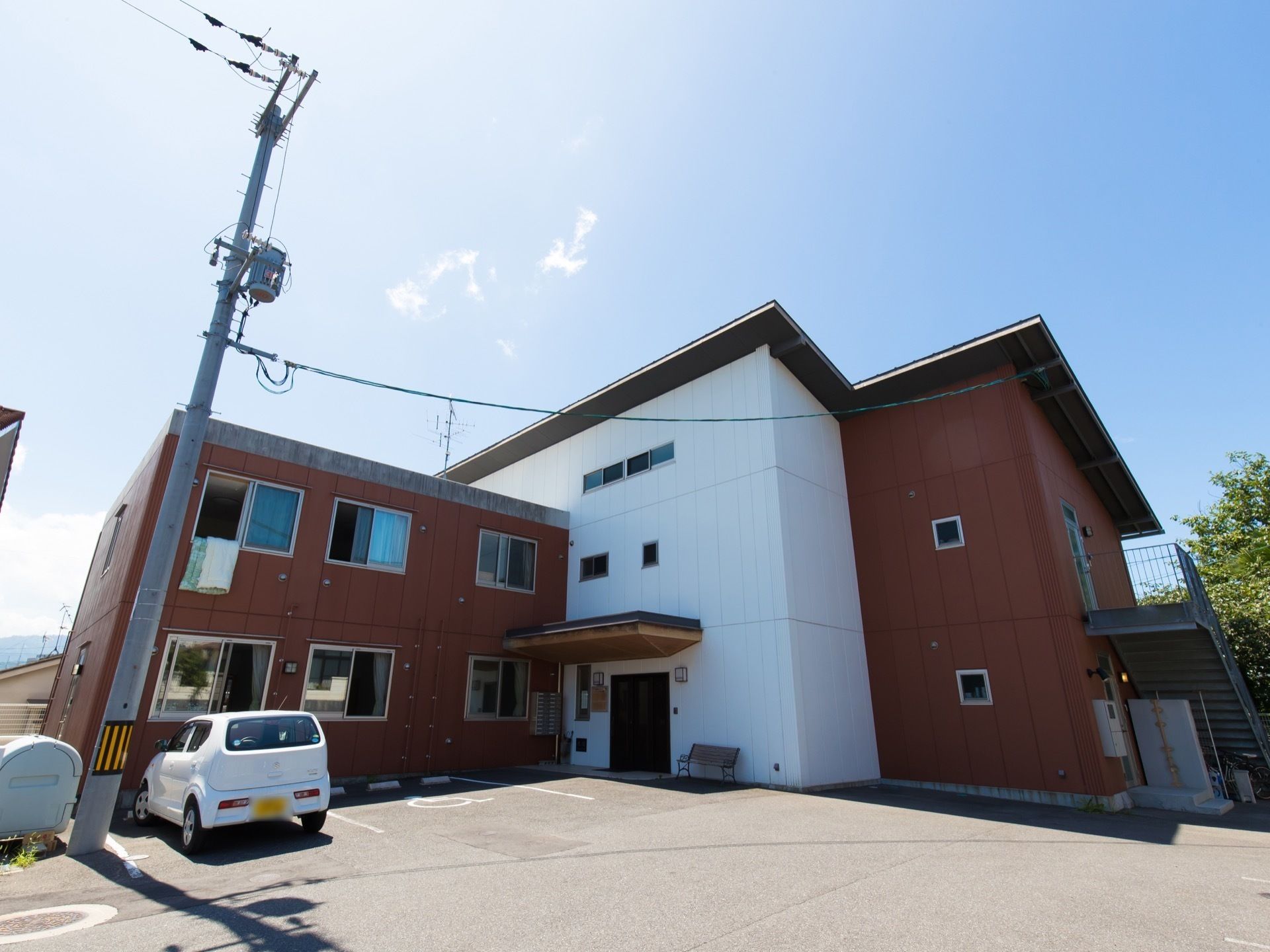 斜めの屋根が備え付けられた、おしゃれな建物である。外壁はグレーとホワイト、ブラウンが施されおりデザイン性が高い。