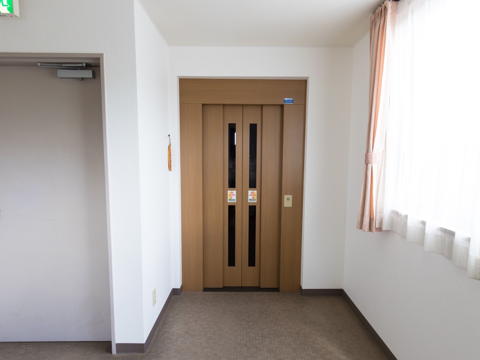 館内には、１基のエレベーターが設置されている。扉は木目調である。レースのカーテンが掛かった窓からは、日差しが差しこんでいる。