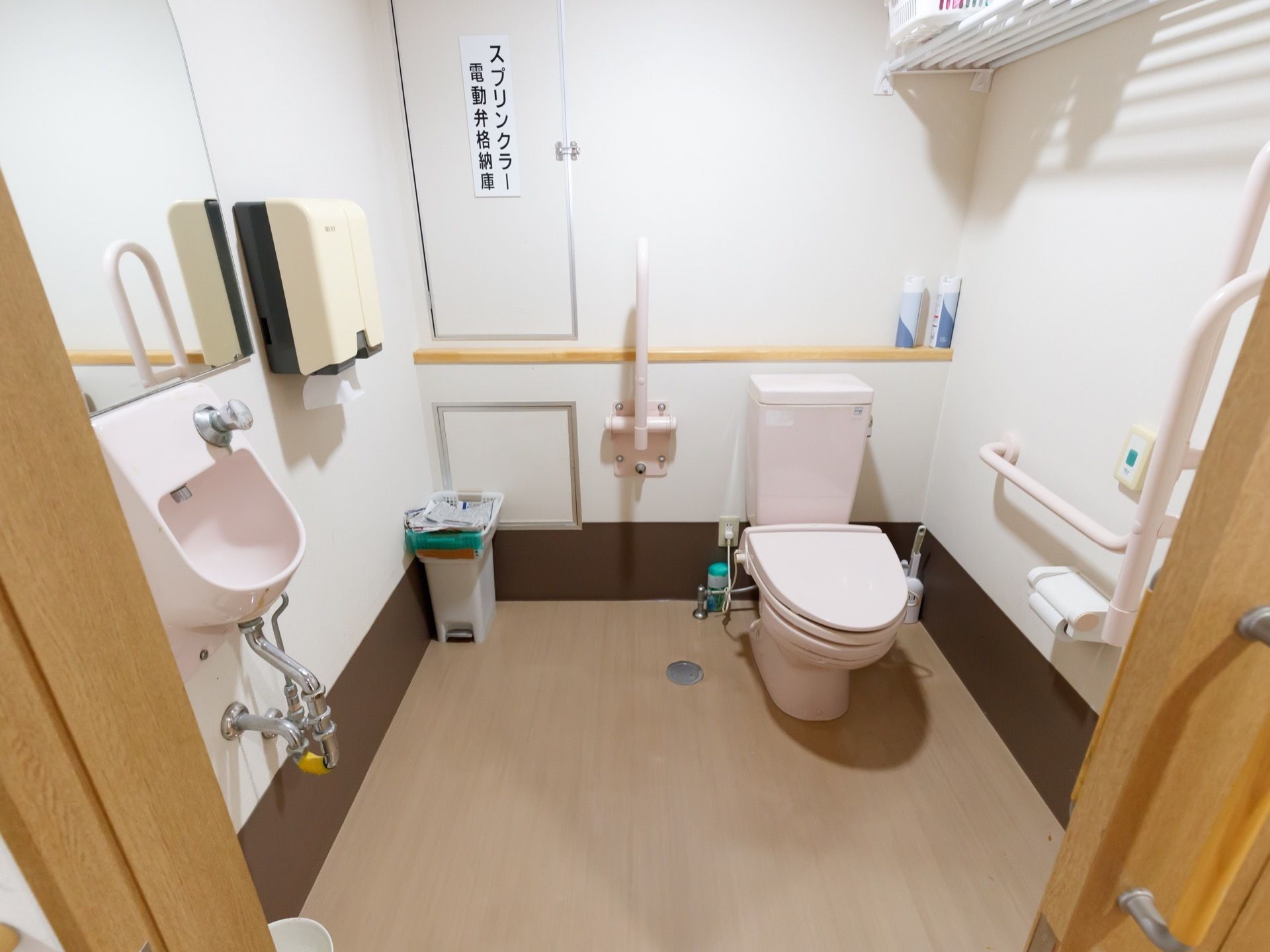 同じ空間に洗面台が備わったトイレである。水平型や可動式の手すり、呼び出しボタンが壁に設置されている。