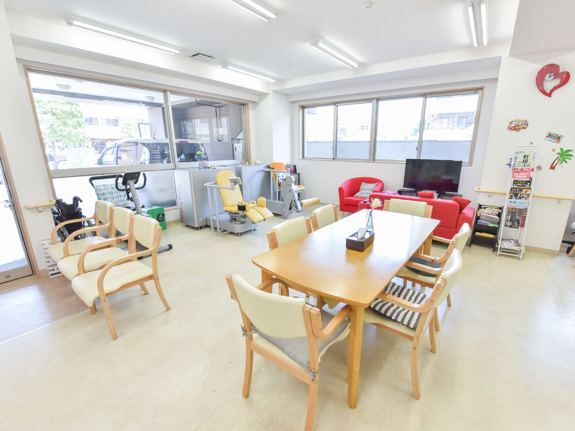 左側には3脚の椅子が横並びで置かれている。右側にはテーブルと椅子がある。正面奥と右奥には窓が付いている。
