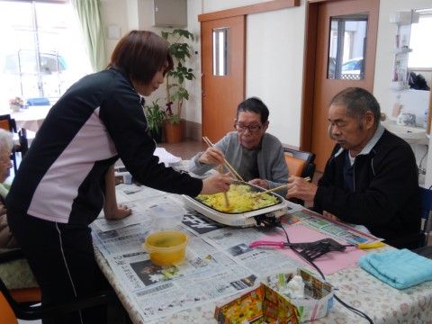 テーブルの上のホットプレートで料理をしている入居者様とスタッフ