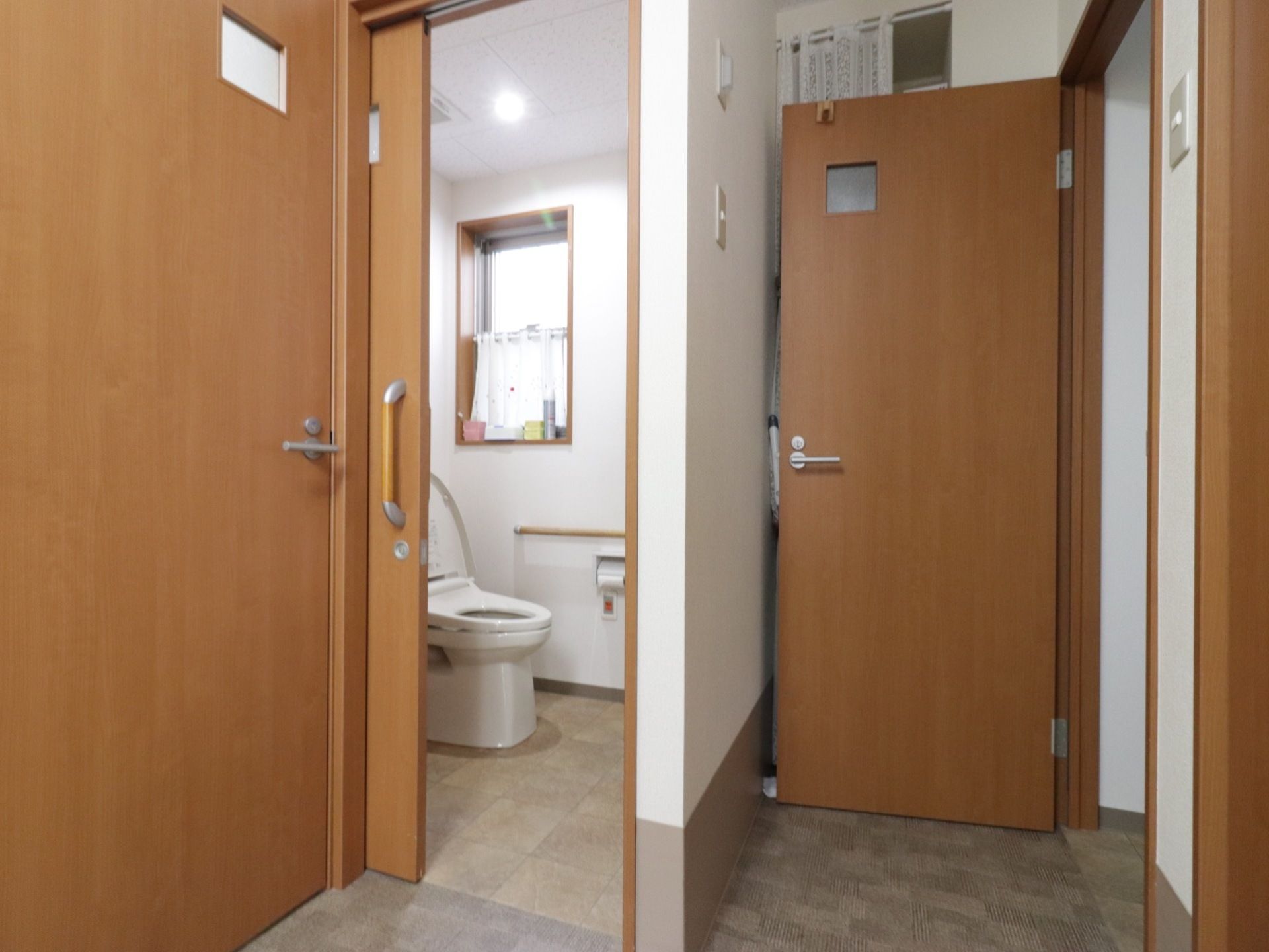 トイレへのドアは開閉しやすい引き戸である。トイレの中には小窓があり、光が差し込んでいる。安全のために手すりが備えられている。