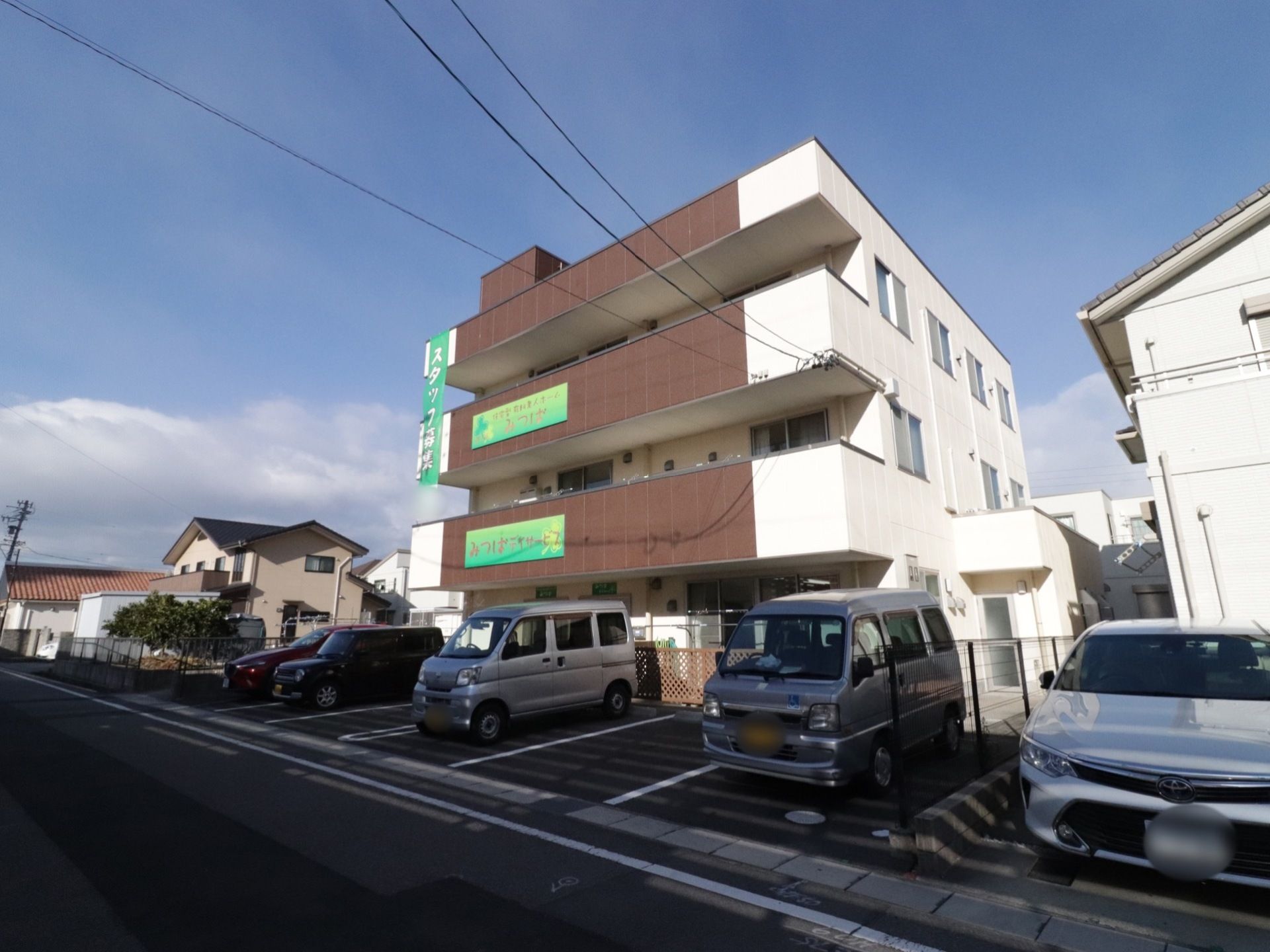 施設の前に駐車場が完備されている。その手前は道路になっている。２階と３階のベランダ側の壁に施設名が掲げられていて、道路からもよく見える。