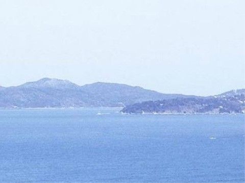 大きな海の先に、山や島が写っている。施設の近くには自然が多く、四季の移ろいを感じることのできる環境である。