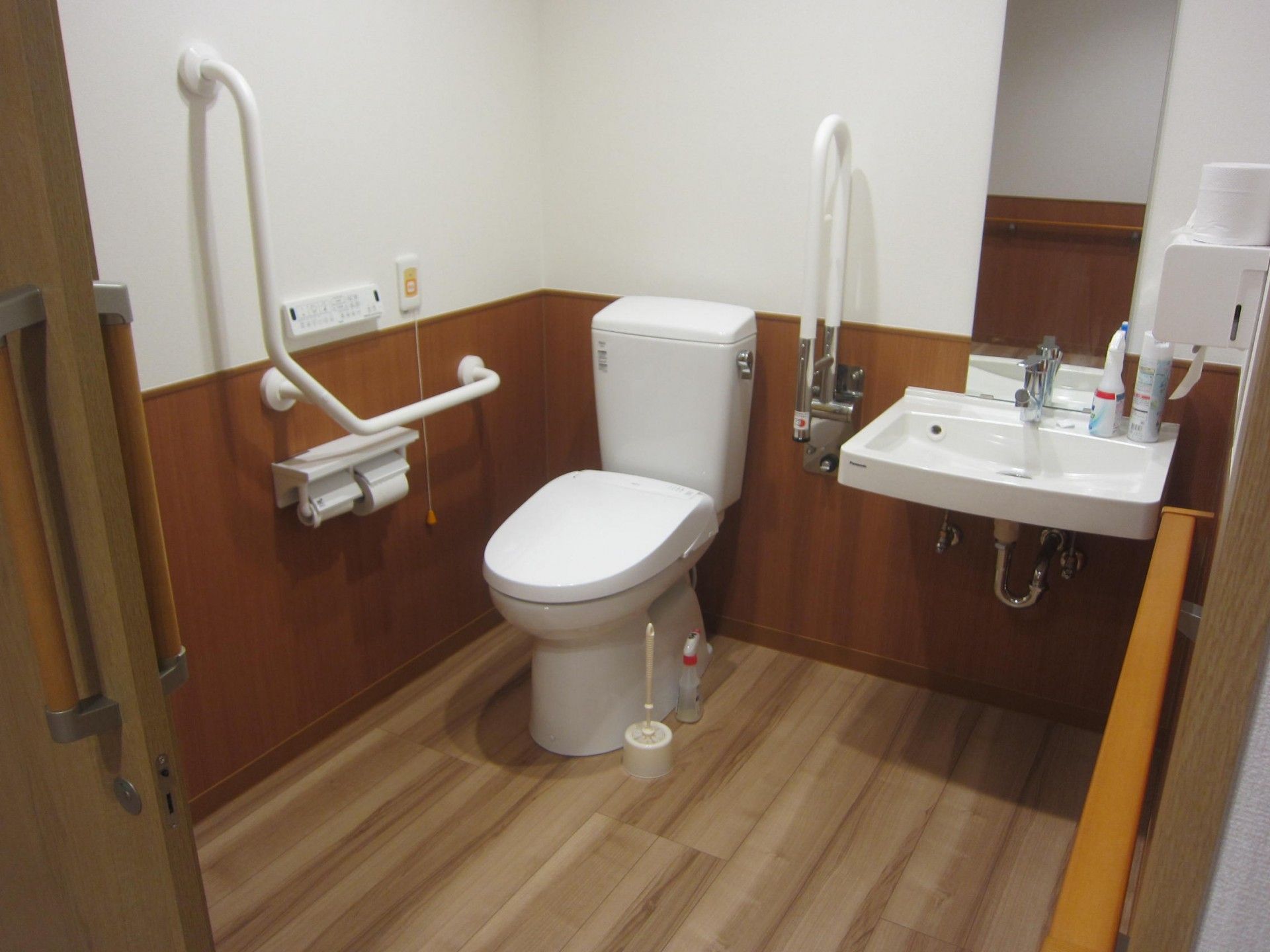 車椅子で入れる広さのある個室である。トイレの壁に、温水洗浄器のリモコンとナースコールのボタンが付いている。