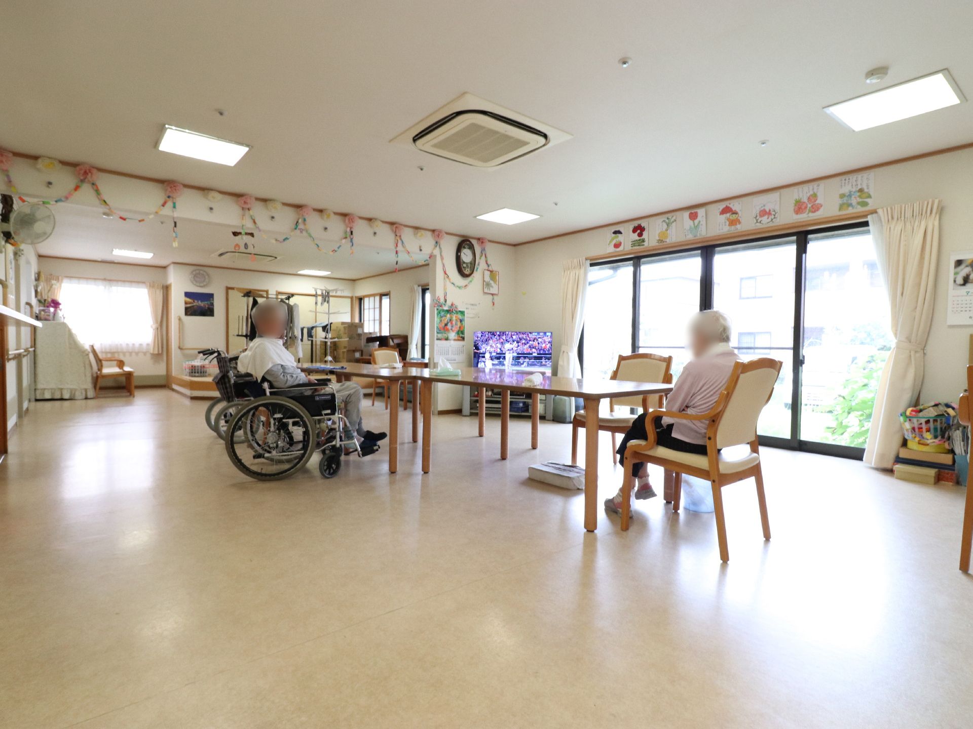 広い空間の真ん中にテーブルが並べてある。天井近くに花や輪っかの飾りがかかっている。左手奥にピアノが置かれている。