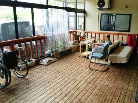 ソファやプランターが置いてあり、窓で囲われているウッドデッキ