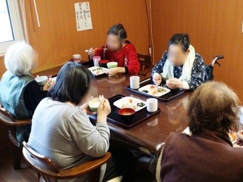 透明のテーブルクロスが掛かっている机で、向かい合って食事をする入居者様たち