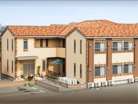 洋風な外壁が印象的な、スロープ付きで玄関周りに緑がある建物