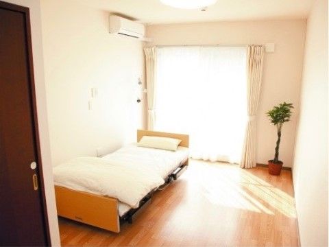 窓辺に観葉植物があり、ベッドがある日当たりの良い居室