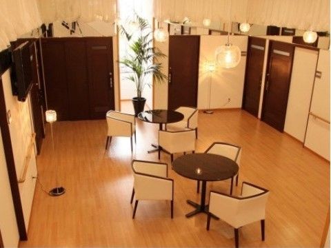 リビングルームには、テーブルと椅子が置かれている。奥の窓からは自然光が差し込んでいる。暖色系の照明が使われており、温かみのある空間である。
