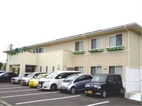 ずらりと車が駐車されている敷地内に建つ、一部にベランダがある建物