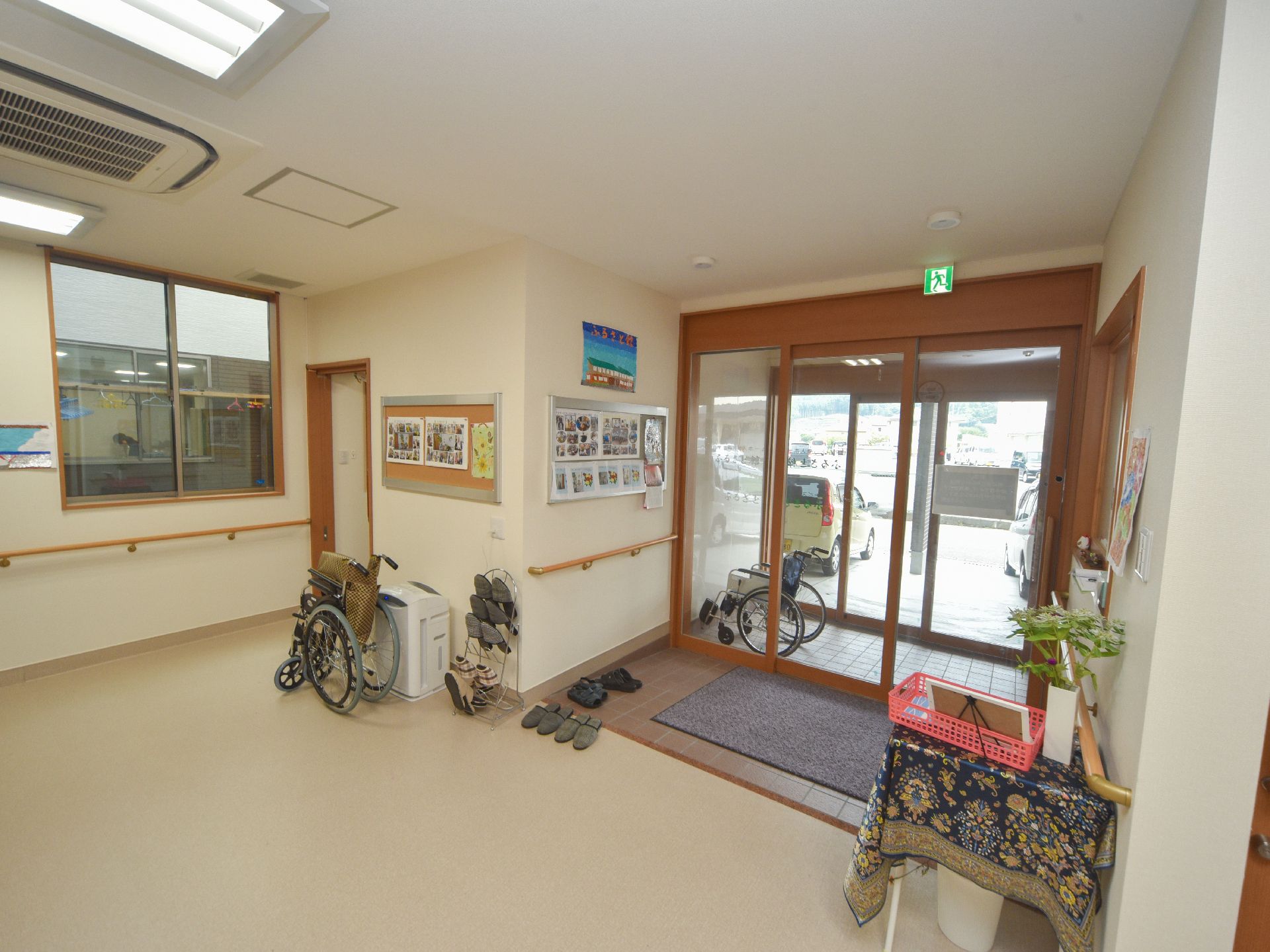 スリッパが並べられており、掲示板に写真が貼られたエントランス