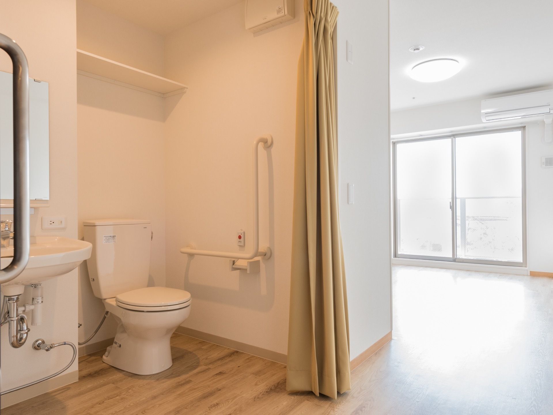 トイレはカーテンで仕切られている。段差がなく、どなたにも安全な造りとなっている。洗面所が設置されている。