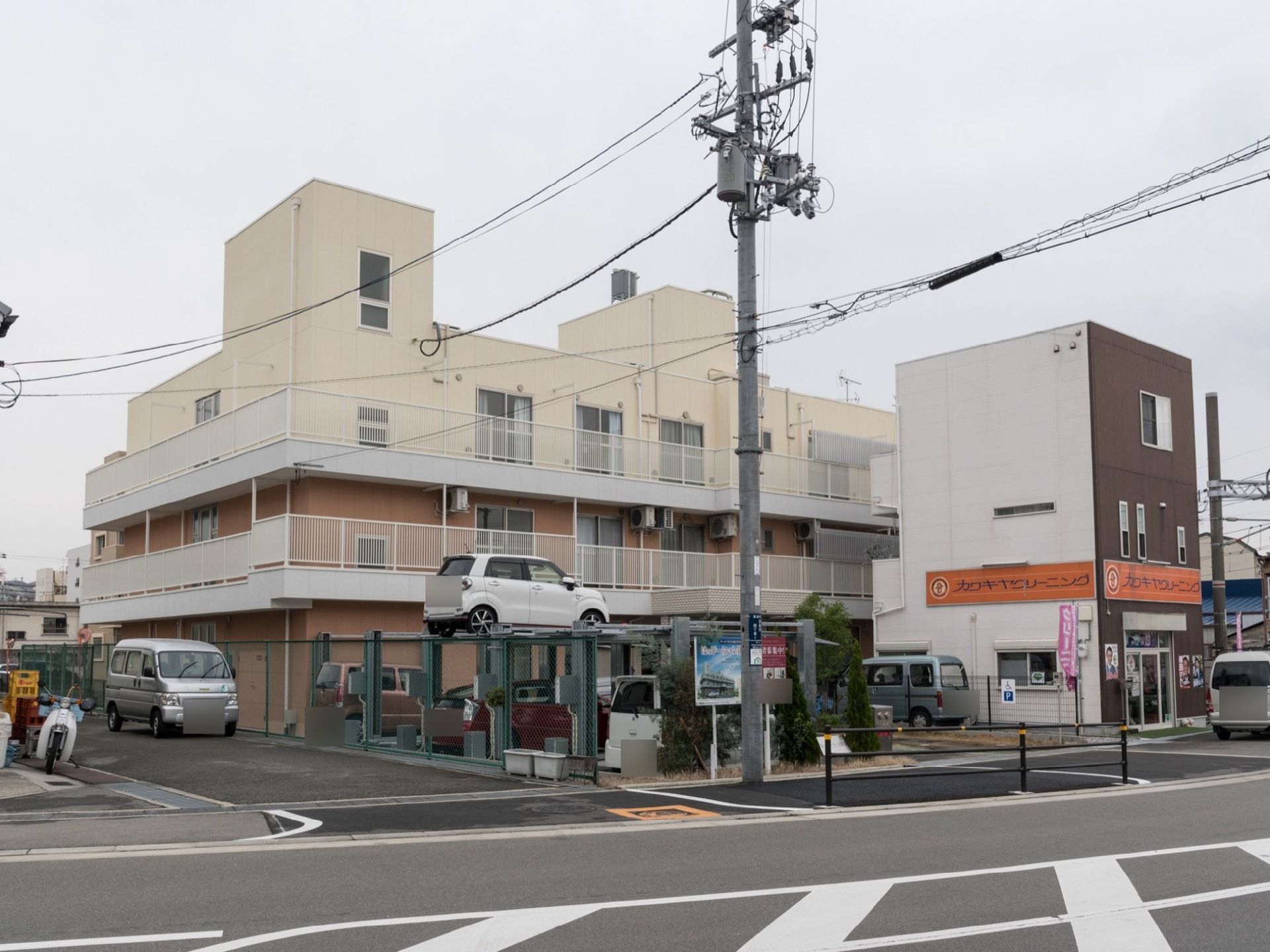 駐車場が設置されている。建物にはベランダがある。クリーニング屋が施設の横にある。大きな道路に面している。