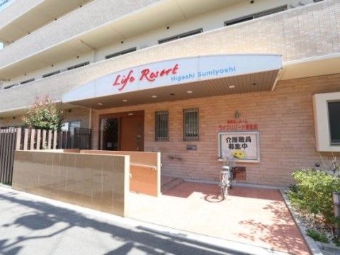 ウッドテラスや緑のある花壇に囲まれている建物の入り口