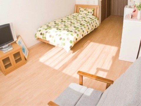 窓辺に一人掛けのソファがあり、家具の揃った日当たり良好な居室