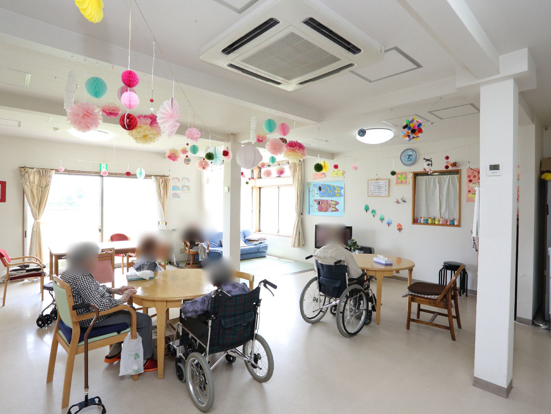 リビングの天井には、季節感のある手作りの飾りが吊るされている。部屋には窓がいくつもあり、太陽の光が差し込んでいる。