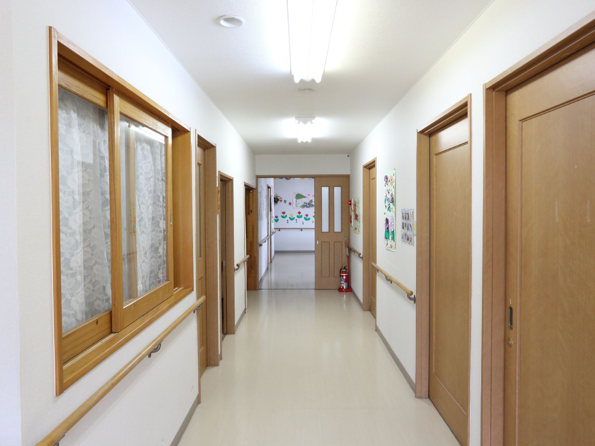 居室をつないでいる廊下には、手すりが設置されている。居室の入口は、横開きのドア。床はフローリングになっている。