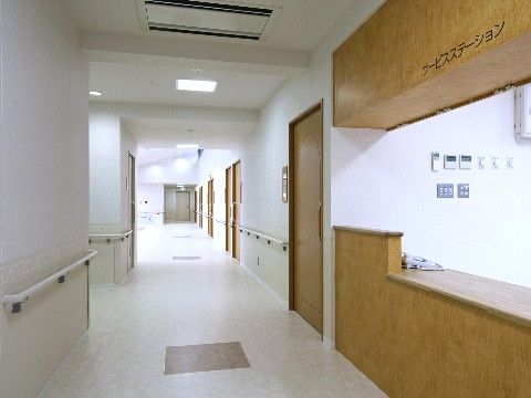 壁に手すりが取り付けられている、白を基調とした廊下