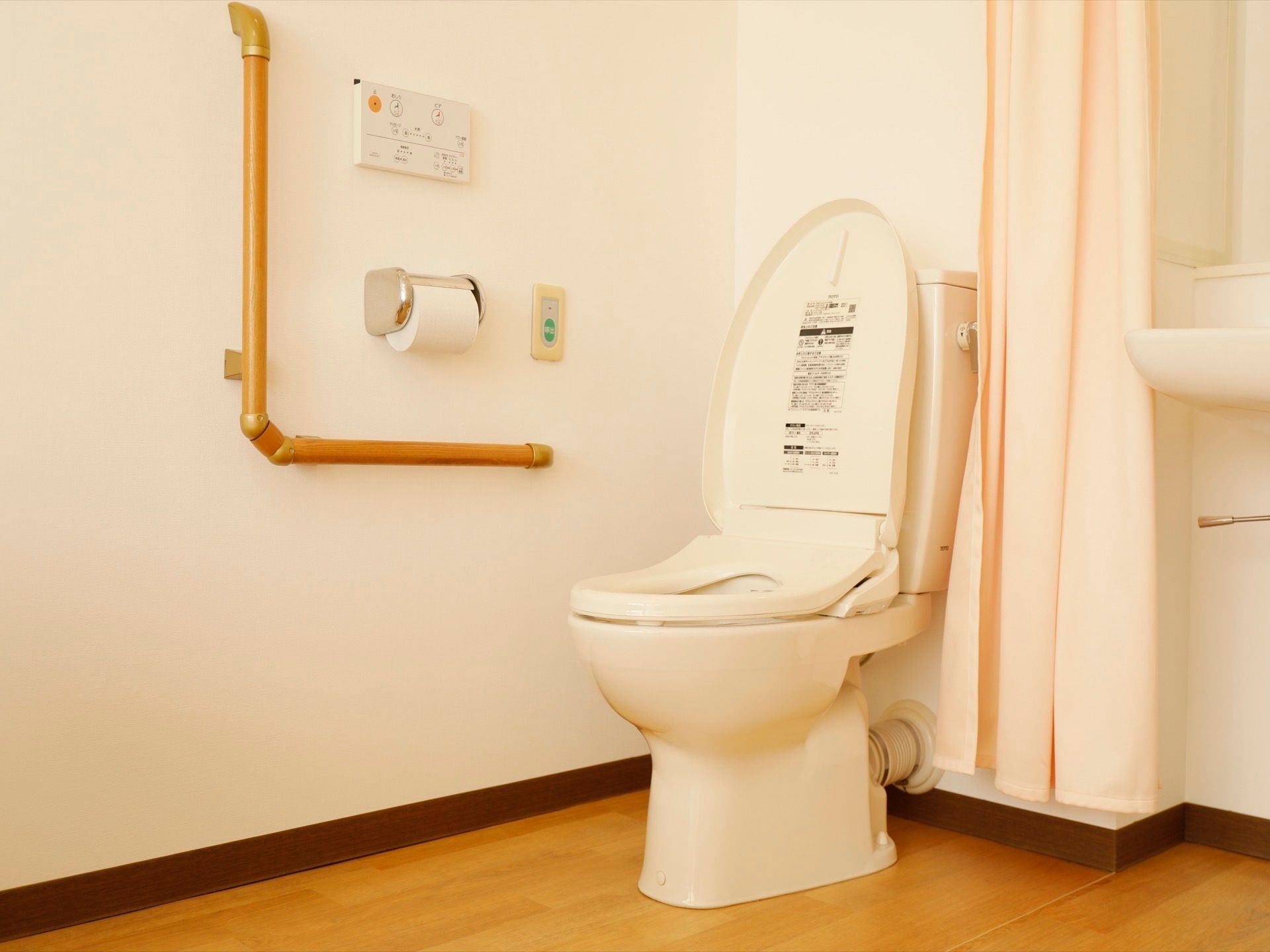 洗浄暖房便座のトイレがあり、カーテンで仕切ることができる。便座横の壁に手すりとナースコールのボタンが設置されている。