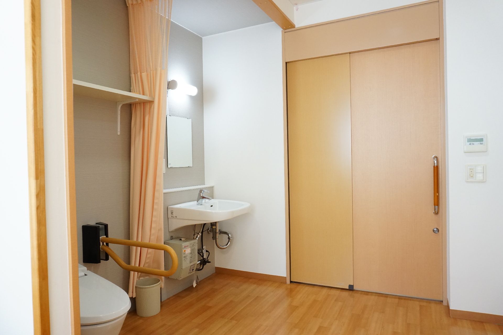 手すり付きのトイレと洗面台が設置された居室