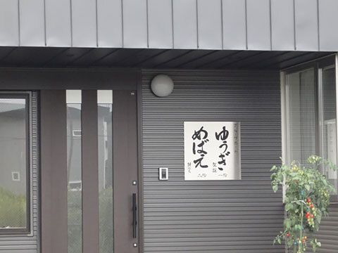 ダークグレーの外壁でモダンな雰囲気が漂うホーム。玄関には２つのユニット名が書かれている。