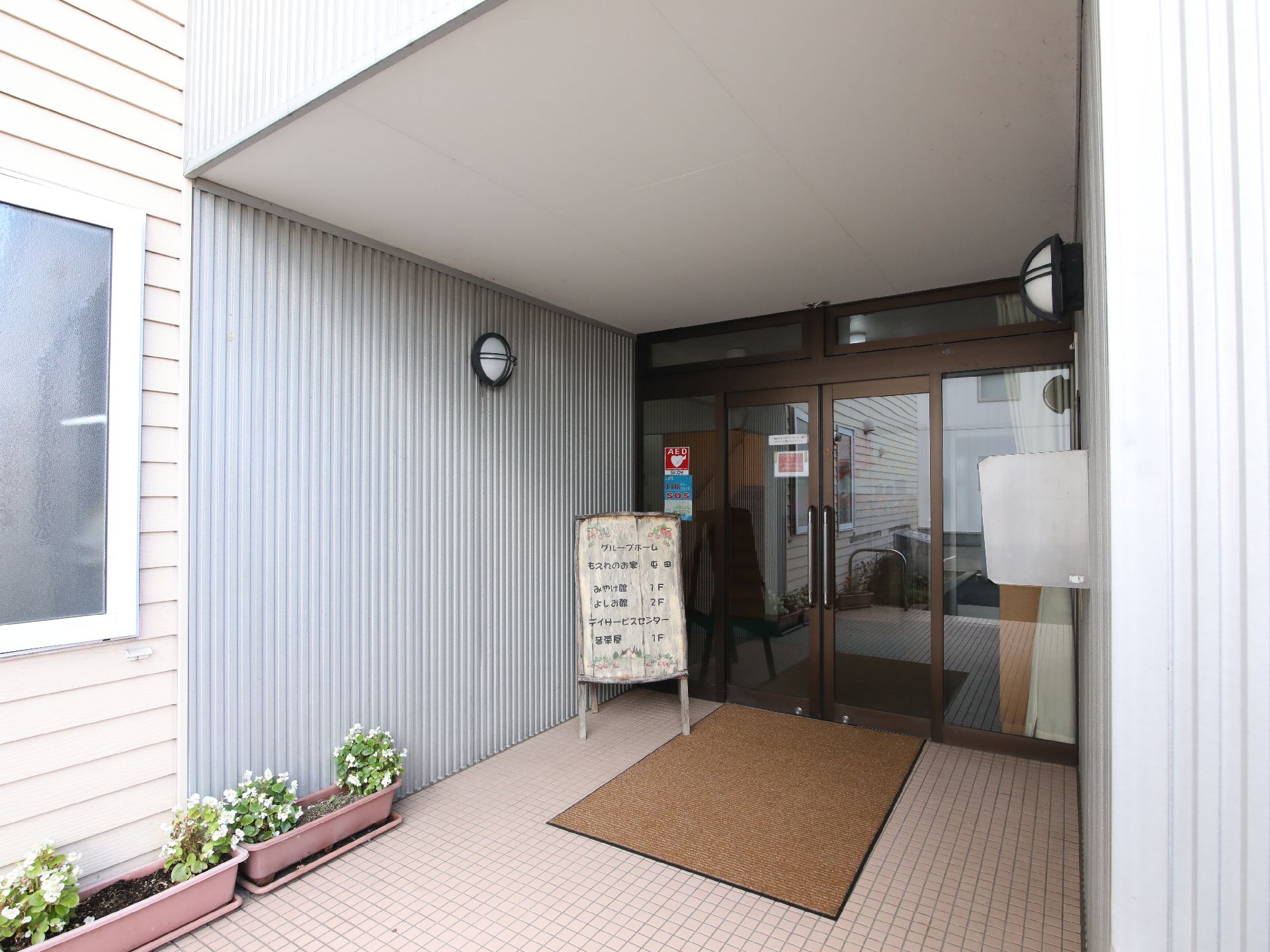 花壇と看板が置いてある玄関