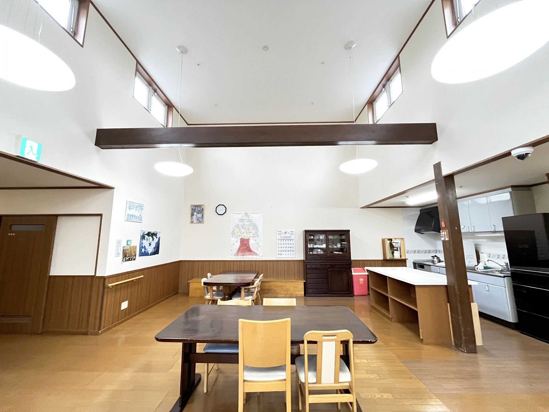 高齢者の方にタオルをかけてマッサージしているスタッフと振り返りながら会話する女性の様子