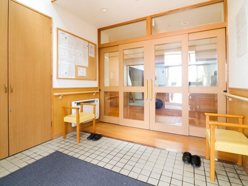 大きなガラス戸が付いた玄関。靴を脱ぎ履きするスペースと館内は仕切られているため外気が大量に館内に入ることはない。ベンチも置かれている。