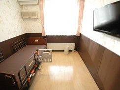 左側にベッドとエアコン、奥のほうに窓がついている小さなワンルームタイプの部屋