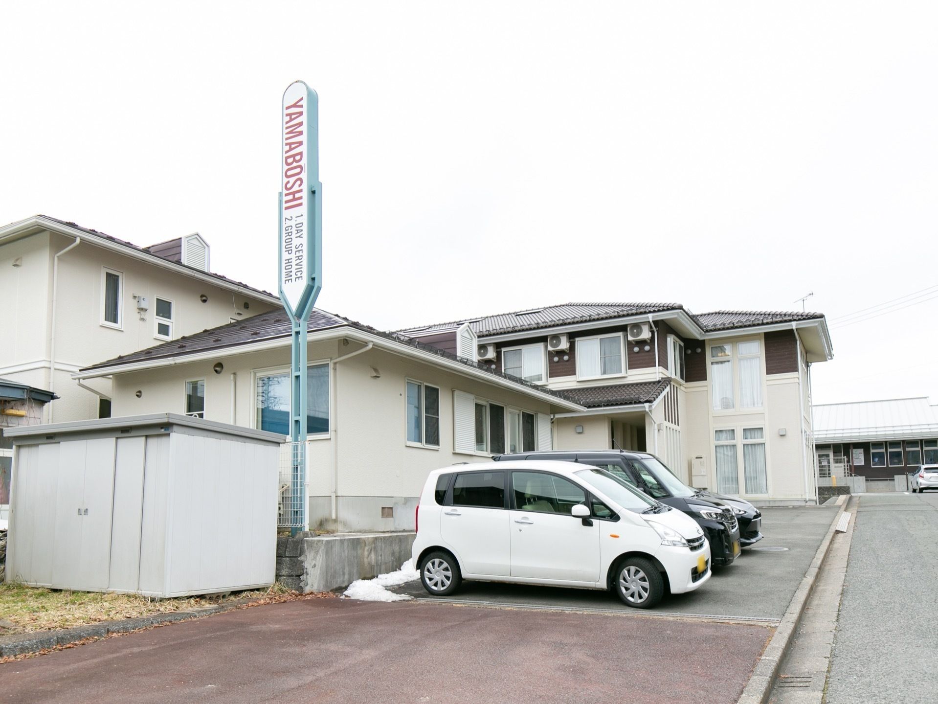 目の前に駐車場があり、看板のある二階建ての洋風な建物