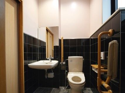 ふたのない便座が付いたトイレの壁には手すりがたくさん付き、車いす対応の手洗い場もある。