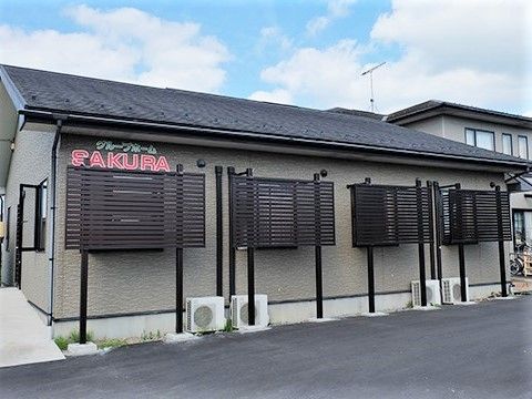 ホーム名がグリーンとピンクで外壁に書かれている建物はブラウン系で三角屋根が付いている。