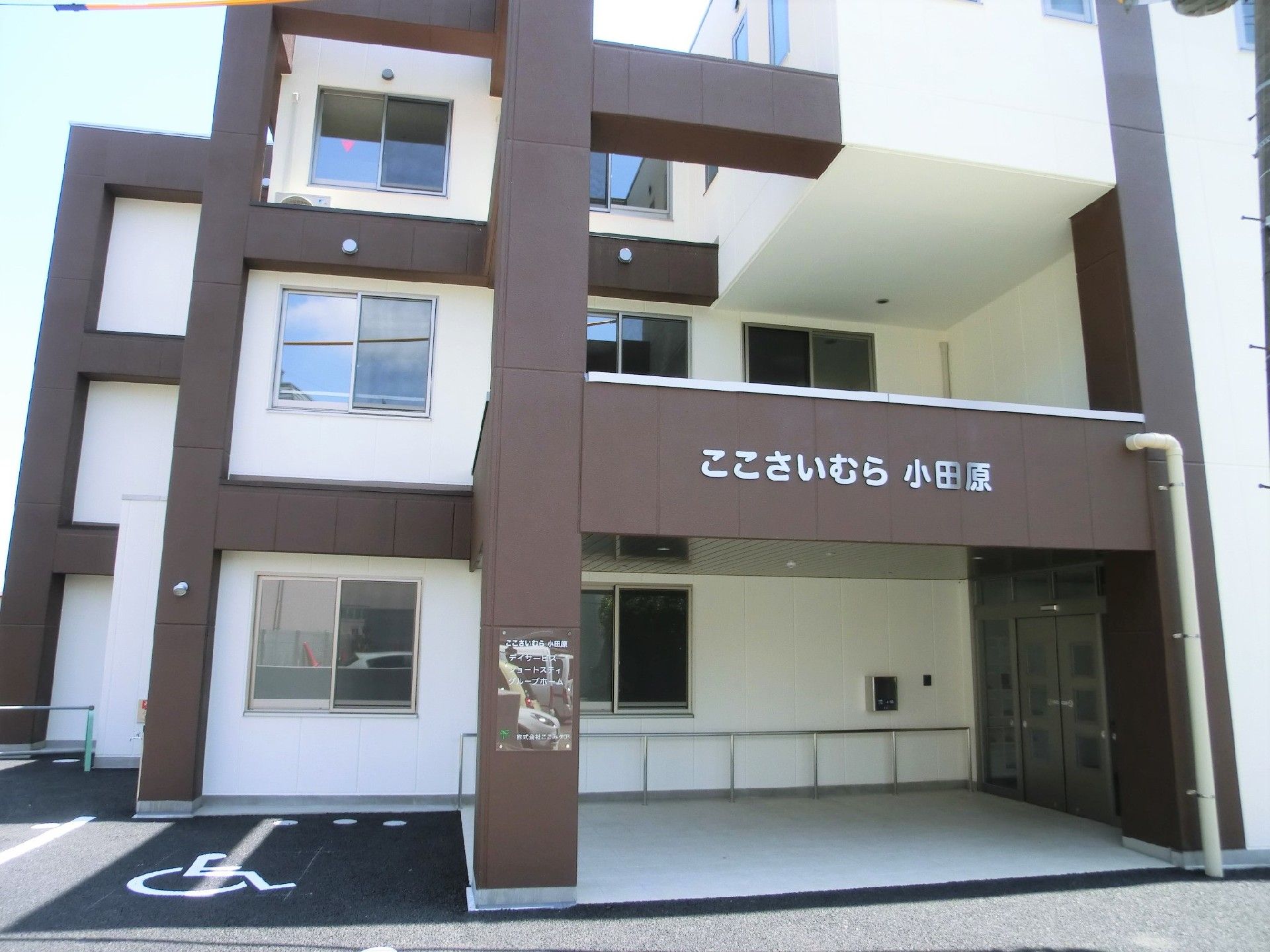 3階建ての建物は白とブラウンをメインとし、玄関周りには手すりもついている。